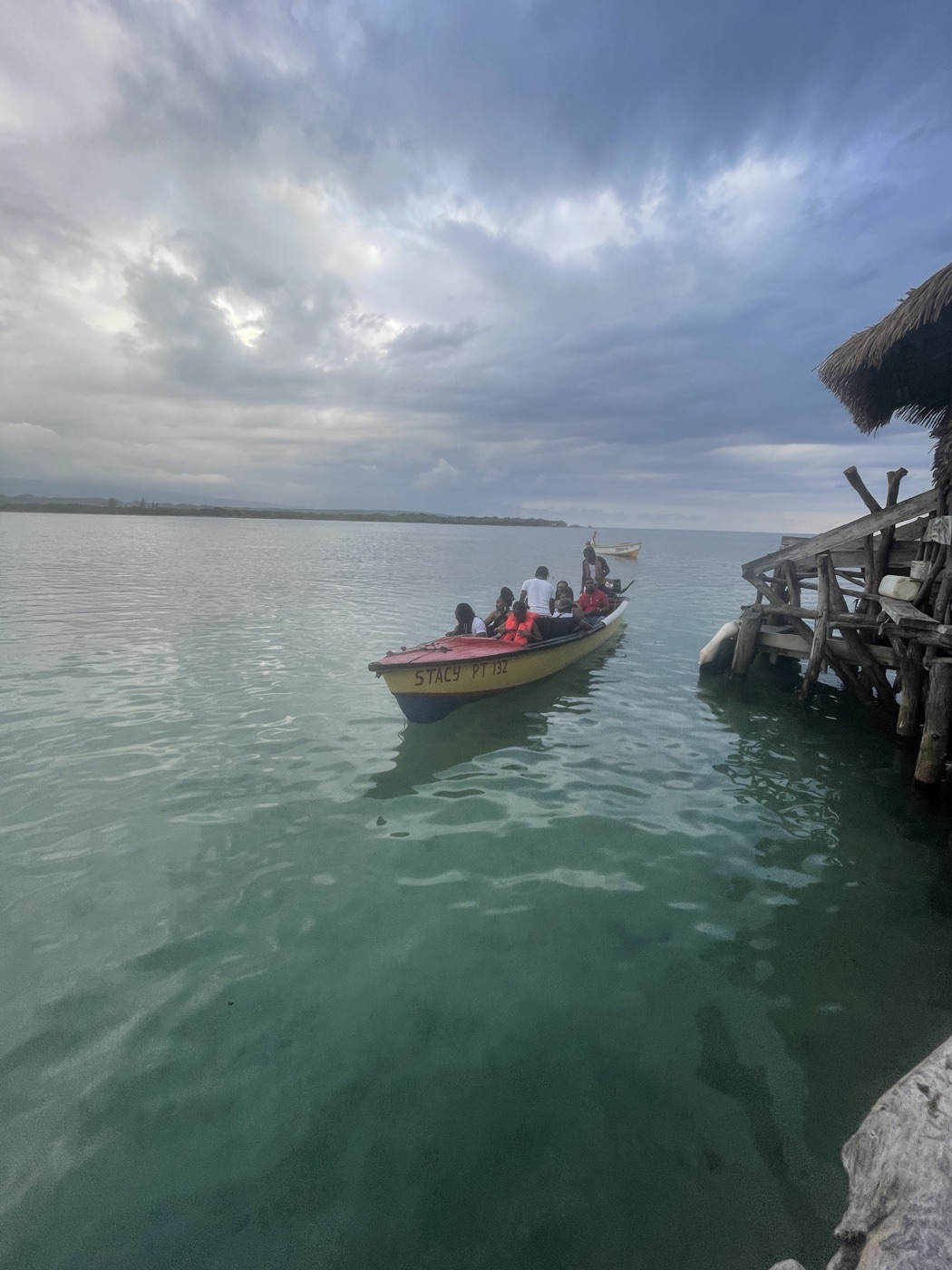 A boatload of visitors in life jackets crossing the water to Floyd's Pelican Bar, the thatched bar on its stilts just ahead