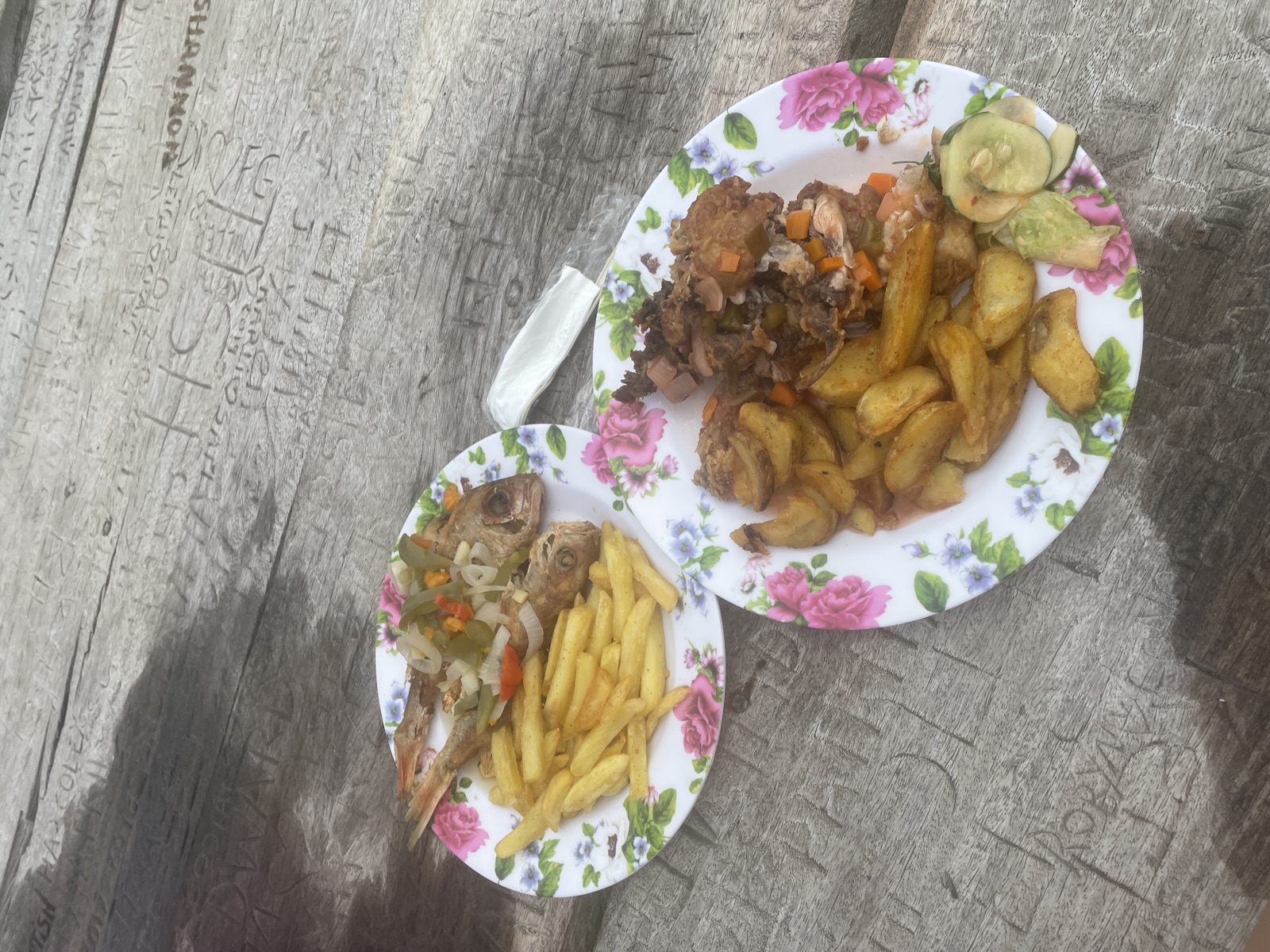 Fresh fried fish and festival served on floral enamel plates atop the carved wooden table at Floyd's Pelican Bar