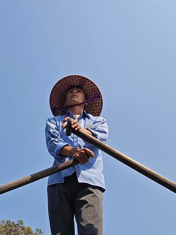 Boatman rowing a bamboo boat through Ha Long Bay