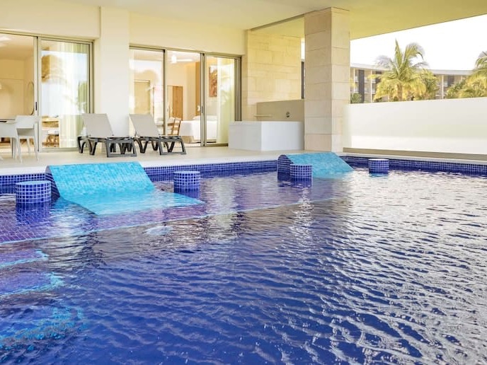 Swim-up suite at Barceló Maya Riviera, with the terrace loungers and in-water sun shelves where the lagoon pool meets the suite doors