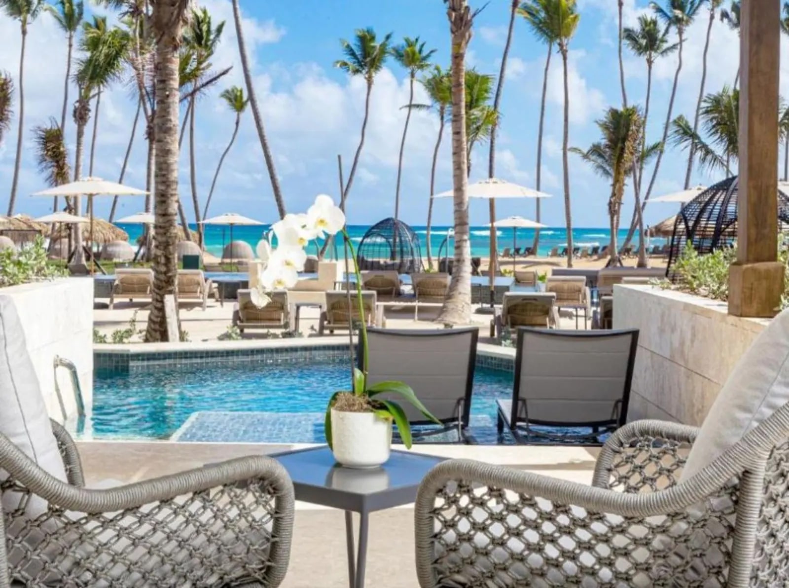 Ocean-front swim-out suite at Secrets Tides Punta Cana, with a terrace pool stepping down from the loungers and the palm-lined beach beyond